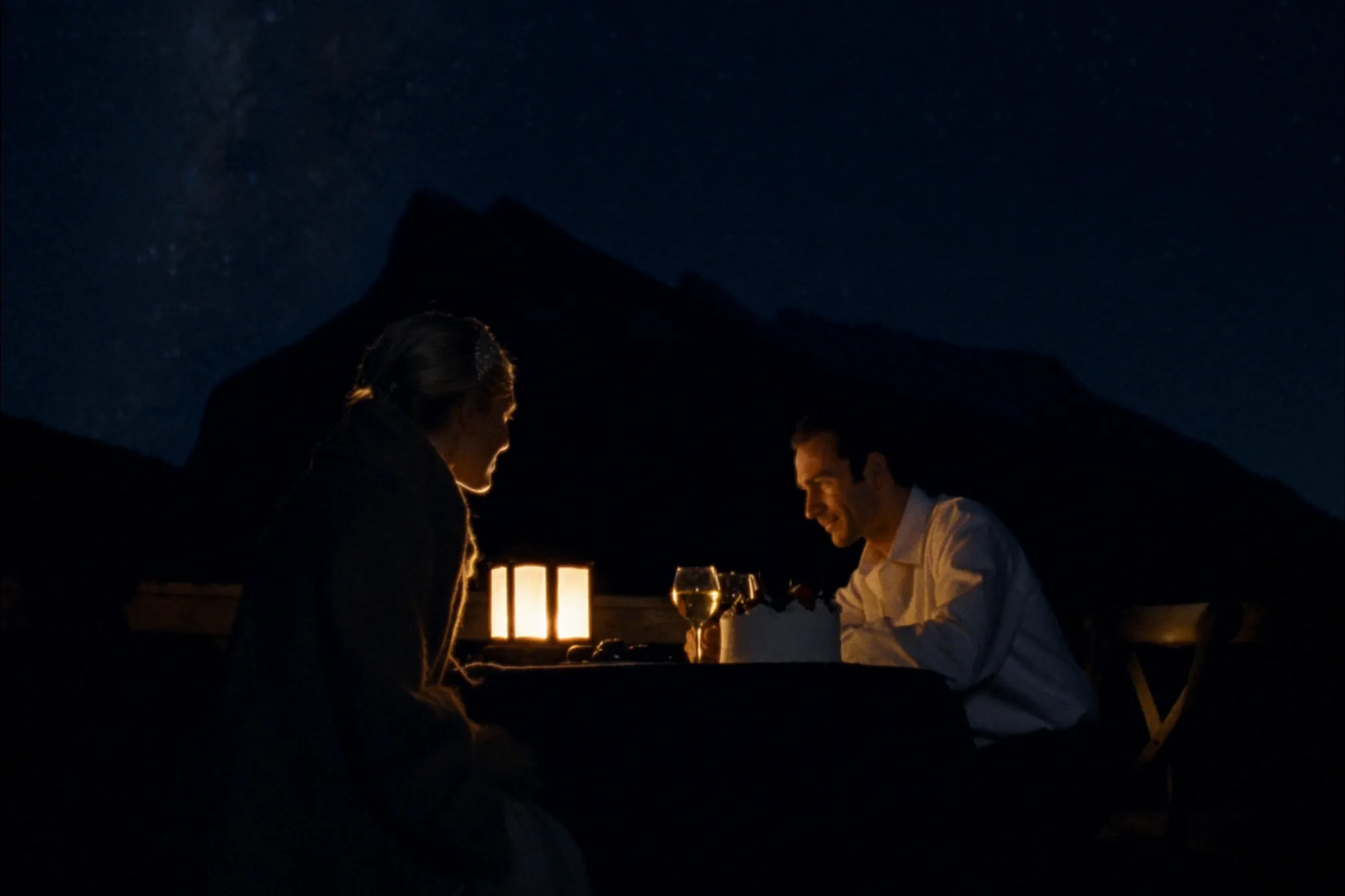 A couple at a candlelit dinner under the stars with Mount Rundle behind