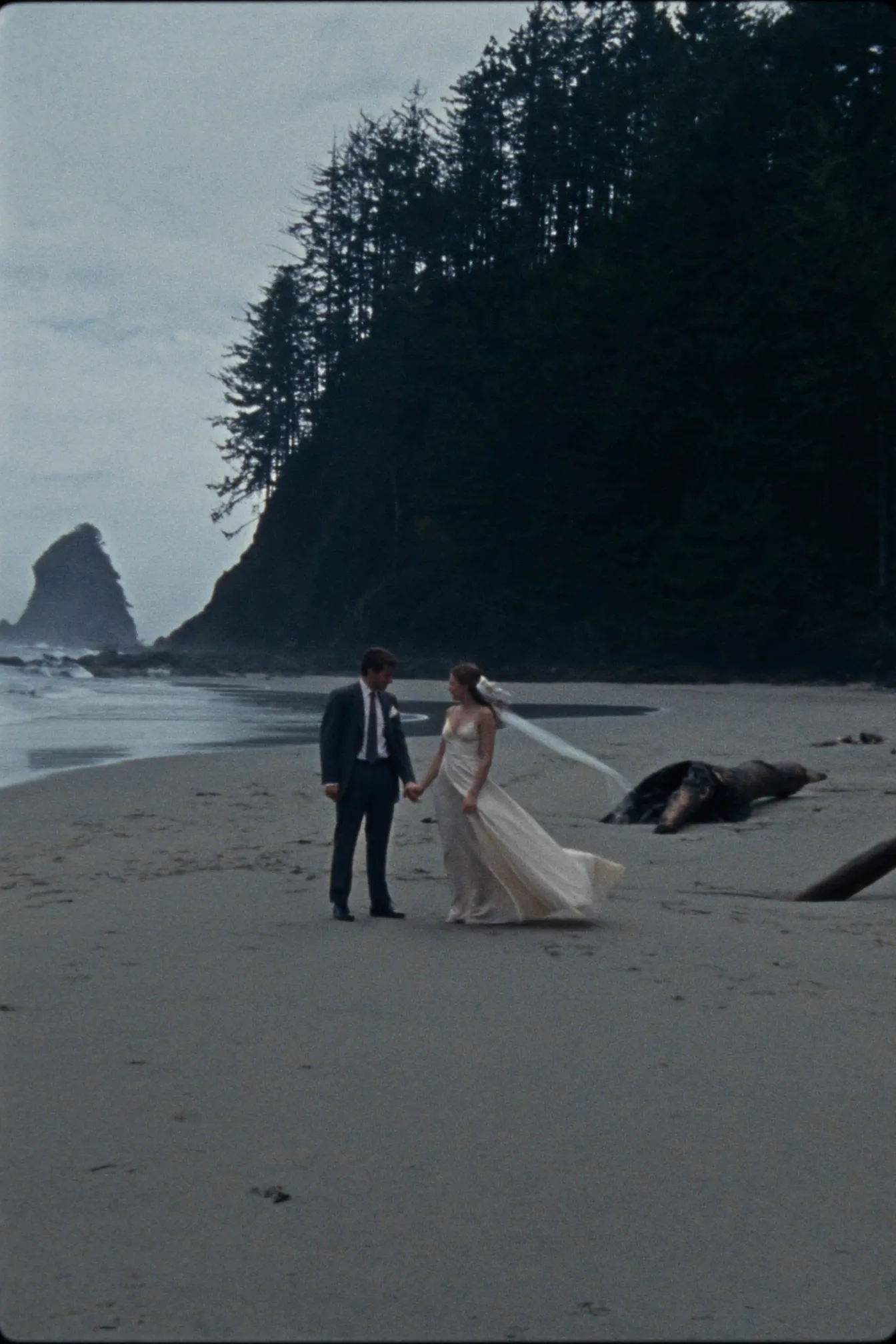 A couple eloping on a wild Pacific beach in Tofino with sea stacks behind them