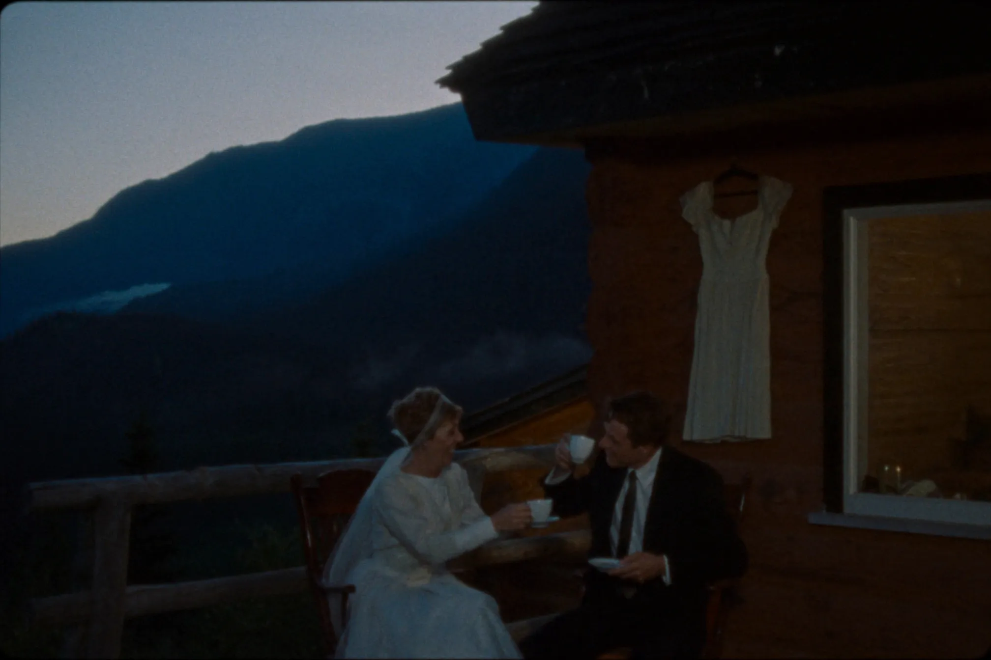 A couple with coffee on a timber cabin deck at dawn in the Columbia Mountains