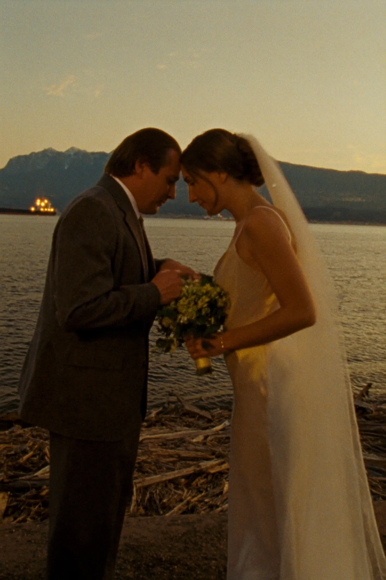 A couple on the Stanley Park seawall at golden hour with the mountains behind
