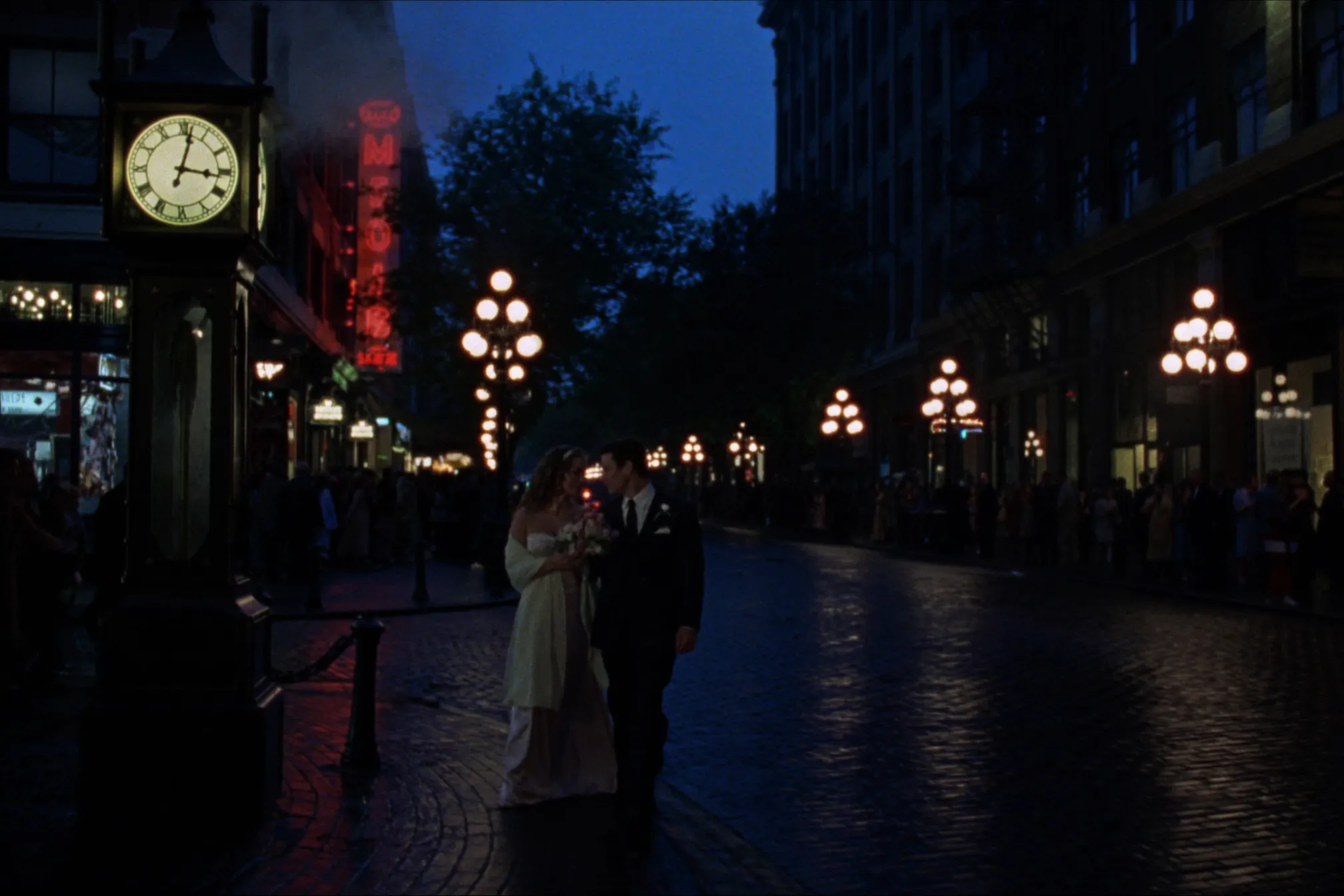 A couple on the wet cobblestones of Gastown at blue hour, gas lamps and neon glowing