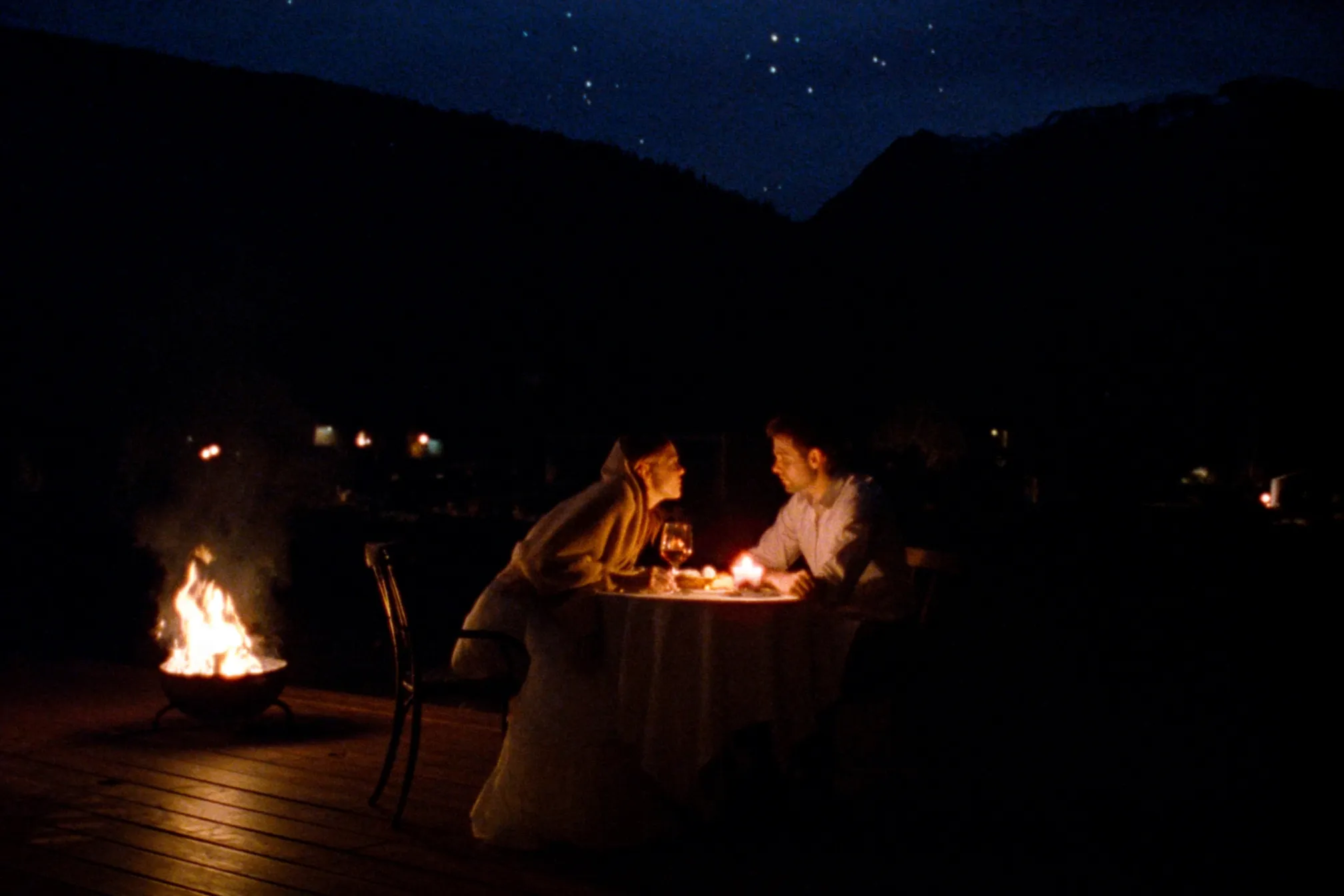 A couple at a candlelit table by a fire under the stars in Whistler